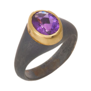 This oxidized sterling silver ring features a 1.6 carat oval amethyst set in an 18k yellow gold bezel.  Call for pricing (#620-1416)