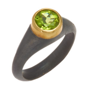 This oxidized sterling silver ring features a 1.25 carat round peridot set in an 18k yellow gold bezel. Call for pricing (#620-1426)