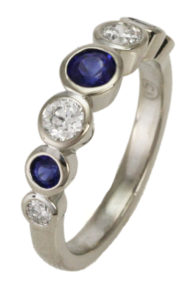 This 18k white gold band features 0.45 cwt. round brilliant diamonds and 0.54 cwt. of blue sapphires.  The stones are bezel set for classic perfection. Call for pricing (#120-0222)
